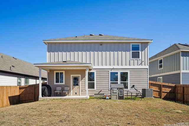 rear view of property featuring central AC unit, a fenced backyard, a lawn, board and batten siding, and a patio area