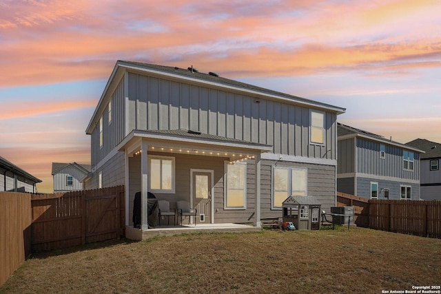 back of property featuring a patio, board and batten siding, a fenced backyard, and a lawn