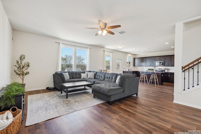 living area with dark wood-style floors, stairs, visible vents, and a ceiling fan