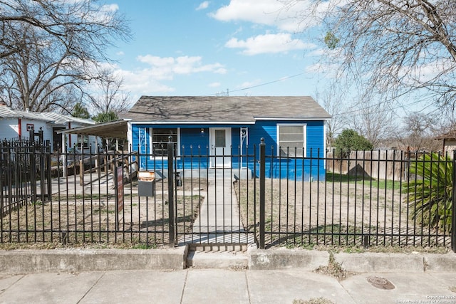 bungalow-style home featuring an attached carport, a fenced front yard, and a gate