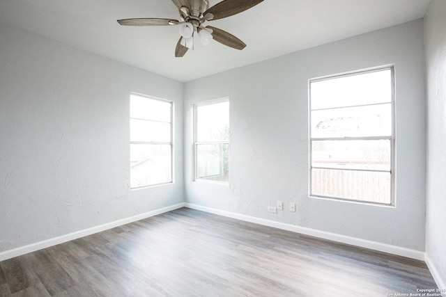 unfurnished room featuring a textured wall, wood finished floors, a ceiling fan, and baseboards