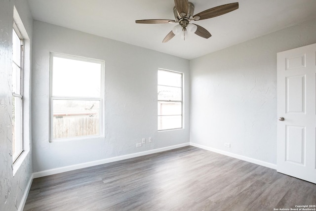 unfurnished room with a ceiling fan, baseboards, and wood finished floors