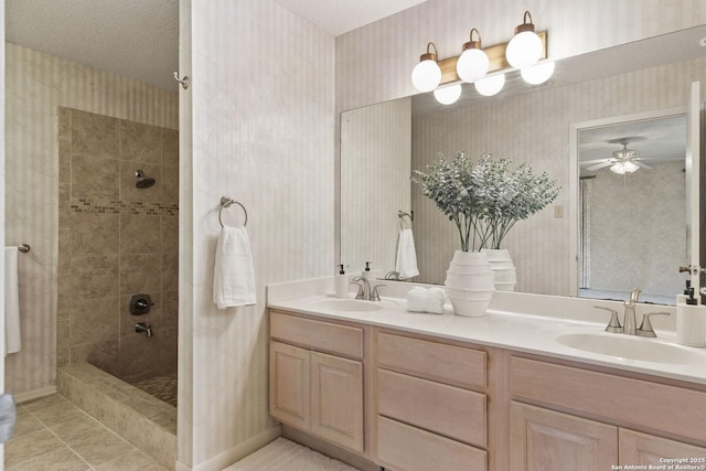 full bath featuring a tile shower, wallpapered walls, and a sink