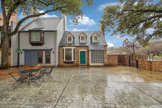 view of front of house featuring stucco siding, fence, and brick siding