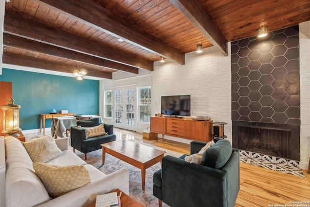 living area with a large fireplace, wood ceiling, wood finished floors, and french doors