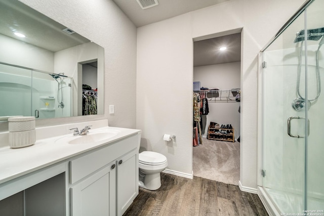 bathroom with vanity, wood finished floors, a shower stall, and toilet