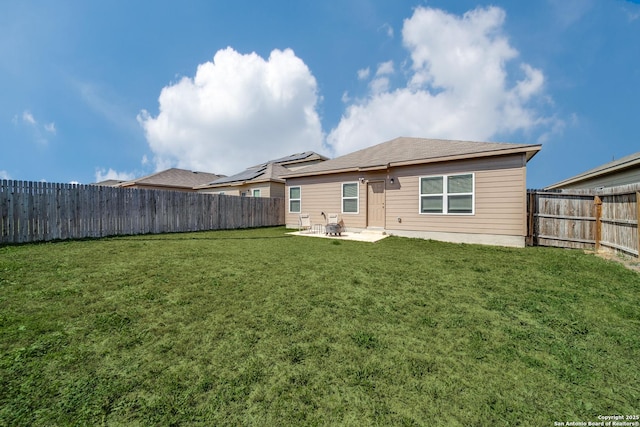 rear view of property featuring a patio area, a yard, and a fenced backyard