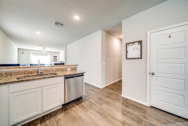 kitchen with light wood finished floors, visible vents, stainless steel dishwasher, a sink, and light stone countertops