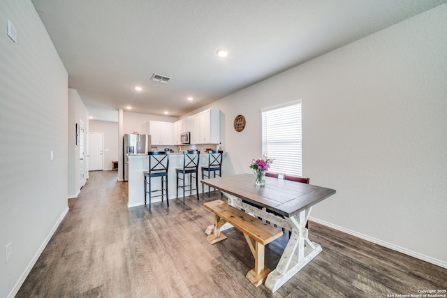 dining area featuring visible vents, baseboards, and wood finished floors