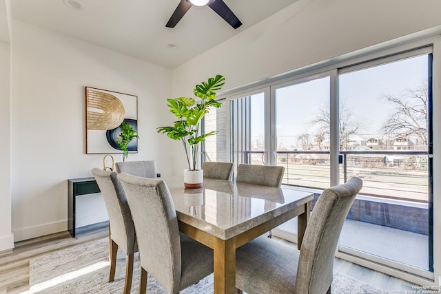 dining area featuring ceiling fan, light wood-style flooring, and baseboards