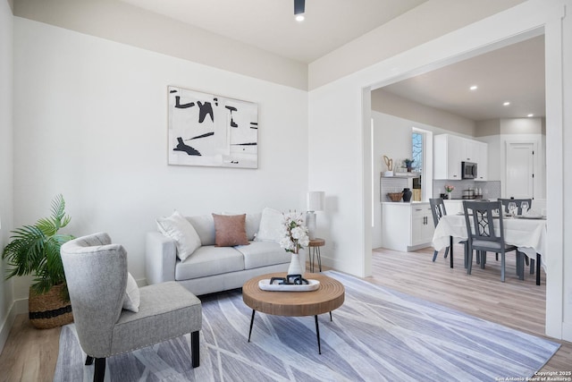 living room with light wood-type flooring, baseboards, and recessed lighting