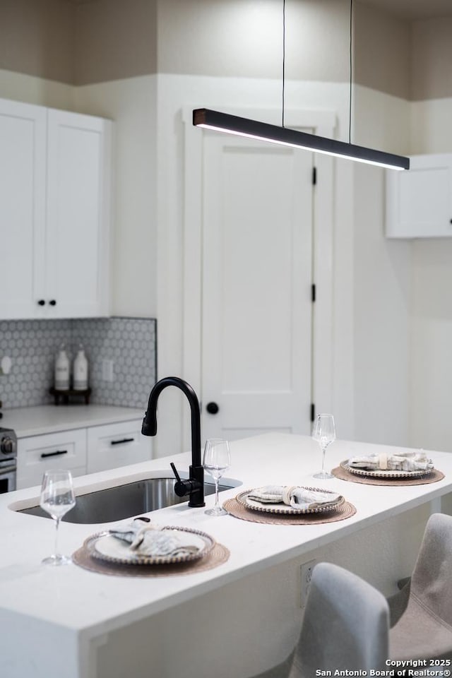 kitchen with backsplash, a sink, and white cabinetry