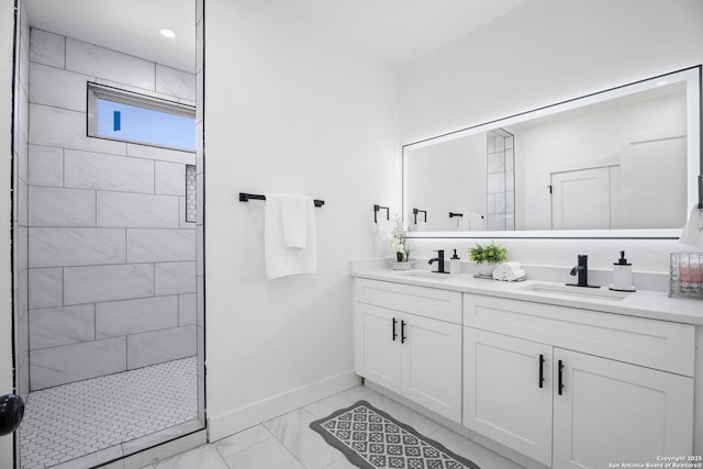 full bath featuring double vanity, baseboards, marble finish floor, a walk in shower, and a sink