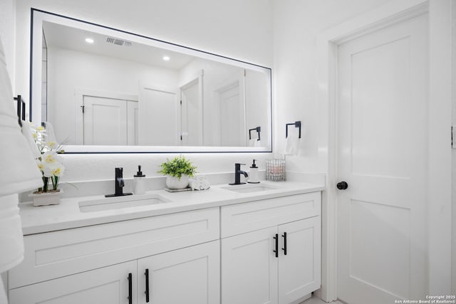 bathroom with visible vents, a sink, and double vanity