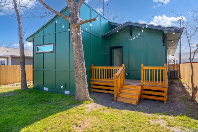 rear view of house with a lawn, crawl space, a deck, cooling unit, and a fenced backyard