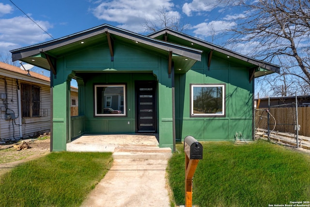 bungalow featuring a porch, fence, and a front lawn