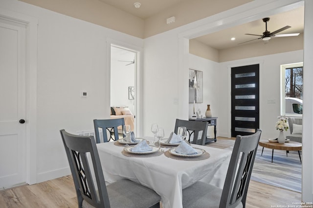 dining space with ceiling fan, baseboards, and light wood-style floors