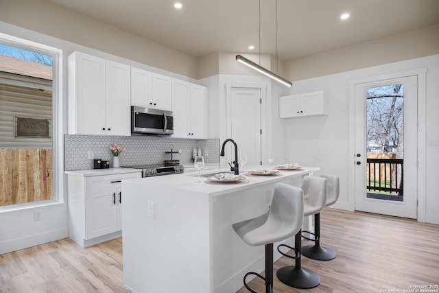 kitchen featuring stainless steel appliances, white cabinetry, a sink, and backsplash