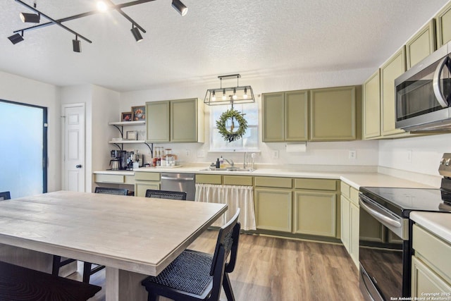 kitchen featuring stainless steel appliances, a sink, and green cabinets