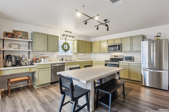 kitchen featuring visible vents, dark wood-style floors, stainless steel appliances, green cabinets, and a sink