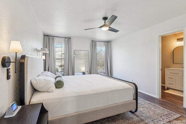 bedroom with ceiling fan, connected bathroom, a textured ceiling, wood finished floors, and baseboards