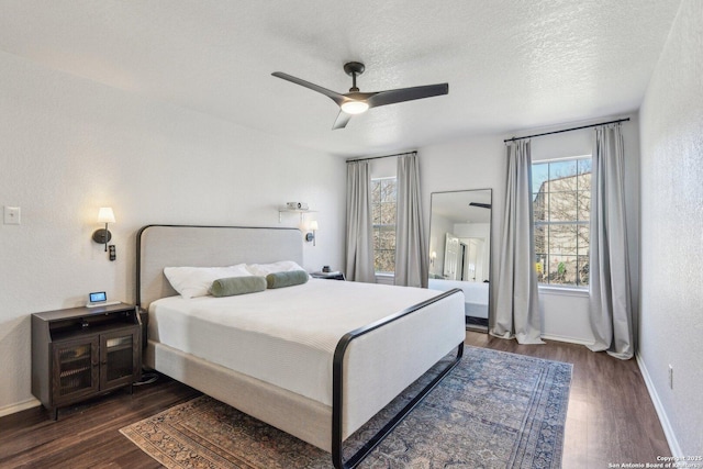 bedroom with dark wood-style flooring, ceiling fan, a textured ceiling, and baseboards