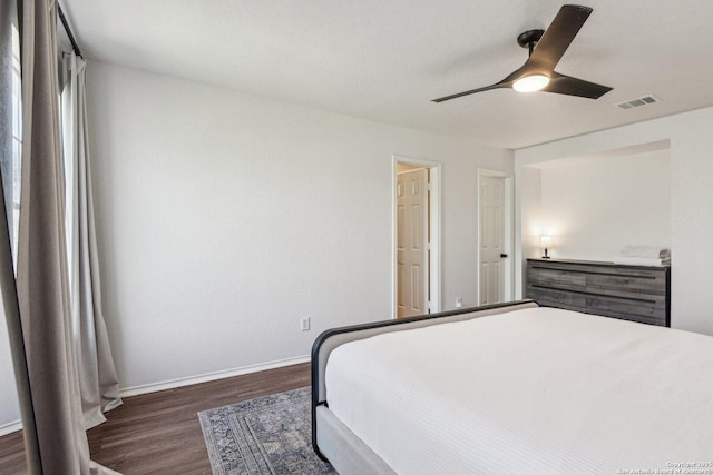 bedroom featuring a ceiling fan, dark wood-style flooring, visible vents, and baseboards