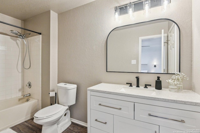 full bathroom featuring a textured wall, vanity, wood finished floors, and toilet