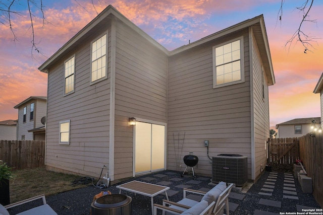 rear view of house featuring a fenced backyard, central AC, and a patio