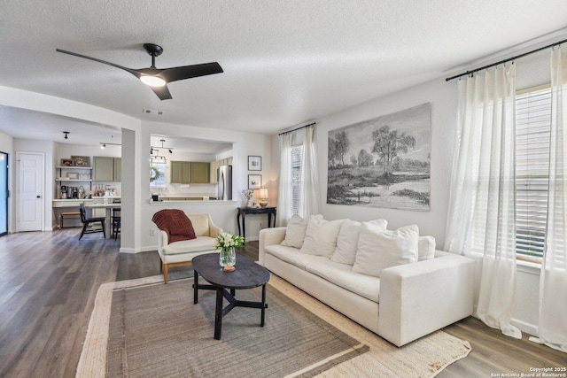 living room featuring a healthy amount of sunlight, visible vents, a textured ceiling, and wood finished floors