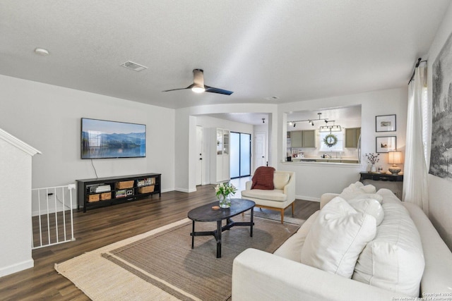 living room with a textured ceiling, wood finished floors, visible vents, and baseboards