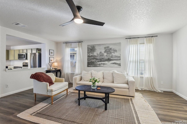 living area with baseboards, visible vents, ceiling fan, wood finished floors, and a textured ceiling