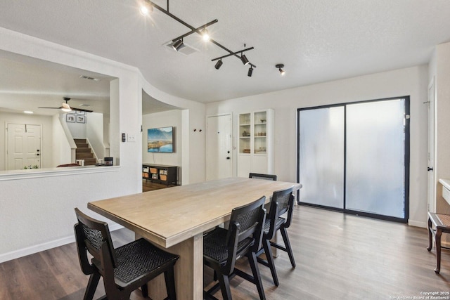 dining room featuring baseboards, a ceiling fan, wood finished floors, stairs, and a textured ceiling