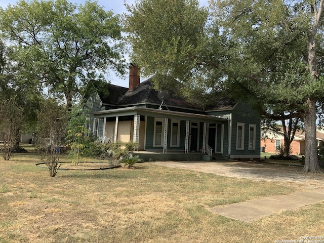 exterior space with covered porch, a yard, a chimney, and a garage