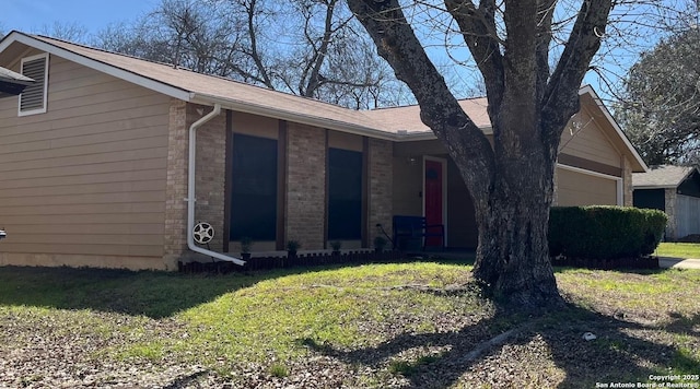 view of property exterior with a yard, brick siding, and an attached garage