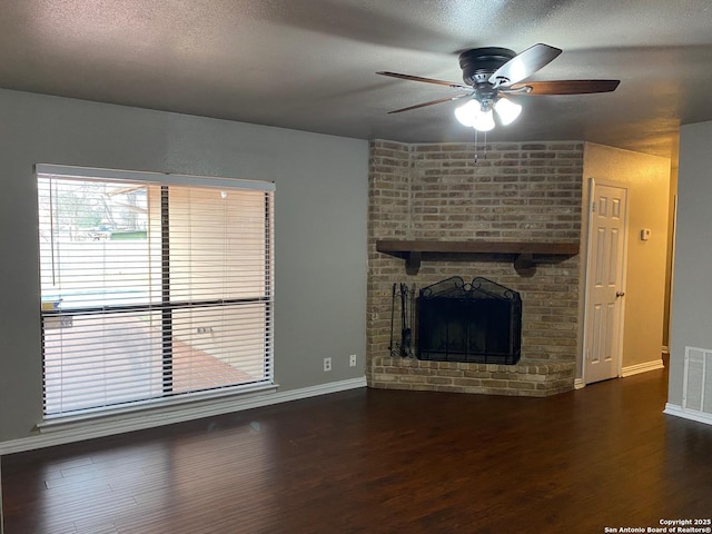 unfurnished living room featuring baseboards, visible vents, wood finished floors, a textured ceiling, and a fireplace