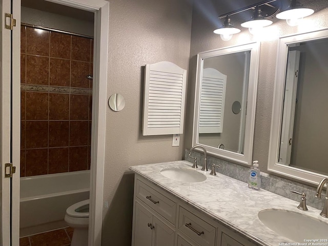 bathroom with double vanity, a sink, toilet, and tile patterned floors