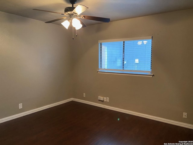 spare room with wood finished floors, a ceiling fan, and baseboards