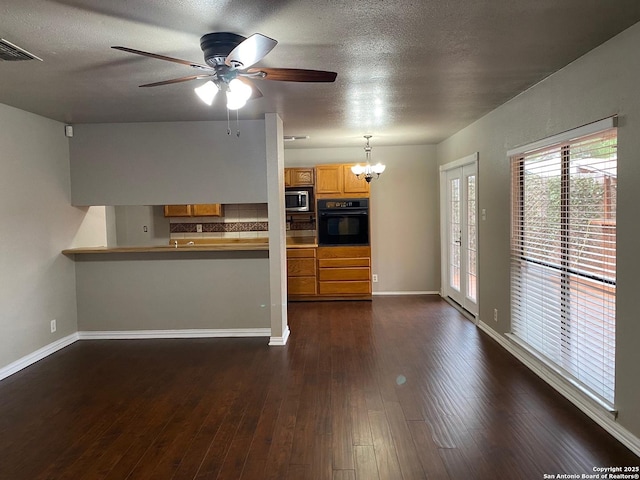 kitchen featuring dark wood finished floors, stainless steel microwave, visible vents, decorative backsplash, and oven