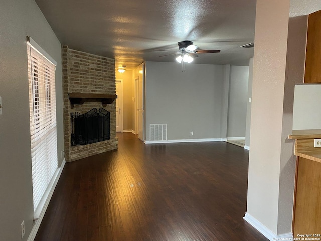 unfurnished living room with baseboards, visible vents, ceiling fan, wood finished floors, and a fireplace