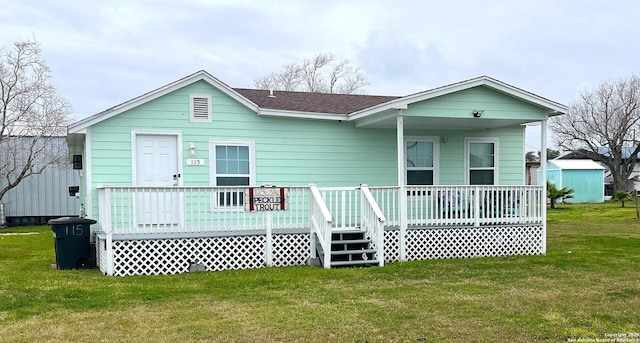 view of front of property with covered porch, a shingled roof, and a front yard