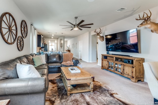 living room with baseboards, a ceiling fan, visible vents, and light colored carpet