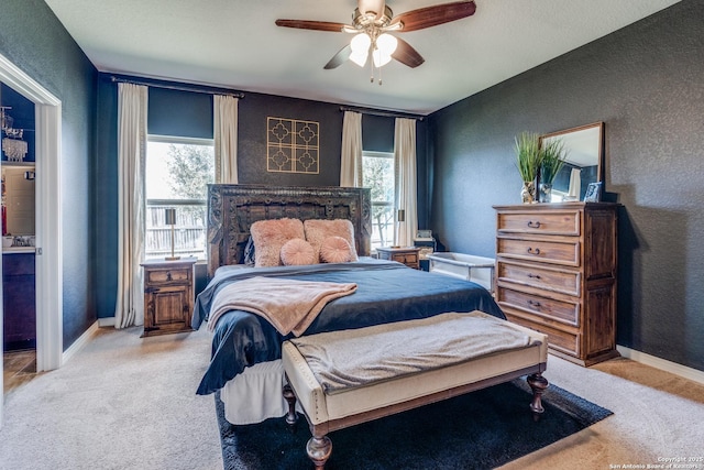 bedroom with light carpet, a textured wall, and baseboards