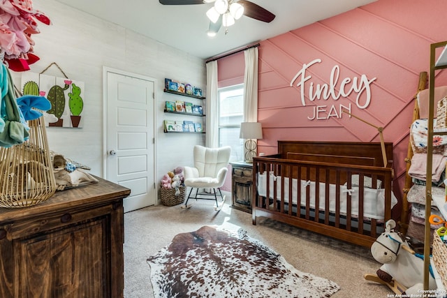 carpeted bedroom with a ceiling fan and a crib