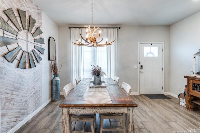 dining area featuring baseboards, a healthy amount of sunlight, an inviting chandelier, and wood finished floors