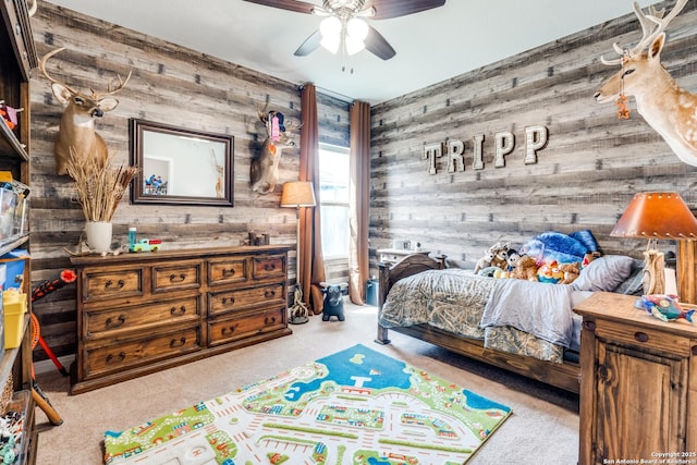 bedroom featuring carpet floors, wood walls, and a ceiling fan