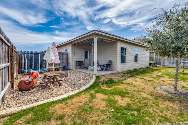 back of property featuring a fenced backyard, a trampoline, a lawn, and a patio