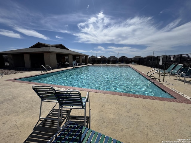 community pool with fence and a patio