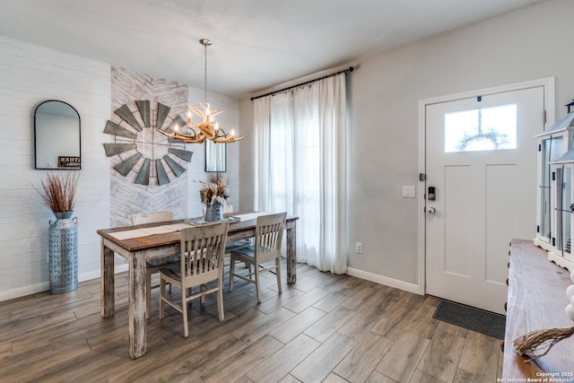 dining area featuring a notable chandelier, plenty of natural light, baseboards, and wood finished floors