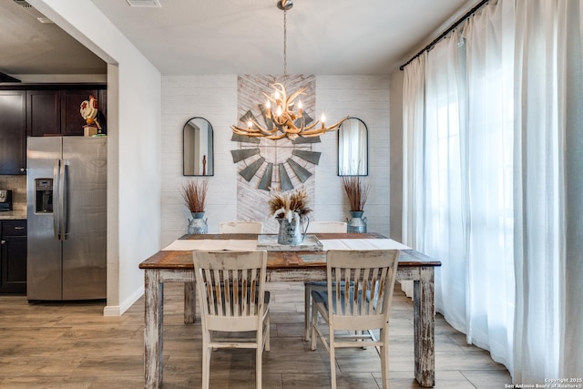 dining room with a chandelier, baseboards, and light wood-style floors